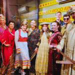 International tourists dressed in traditional Indian costumes posing with Bollywood actors on a movie studio set