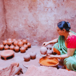 Woman shaping traditional clay pots inside a pottery workshop