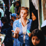 Woman speaking with local residents in a narrow neighborhood lane