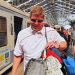 Traveler carrying bags on a busy railway platform beside a train