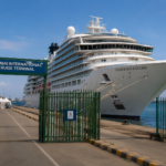 Luxury cruise ship docked at Mumbai International Cruise Terminal under a clear blue sky.